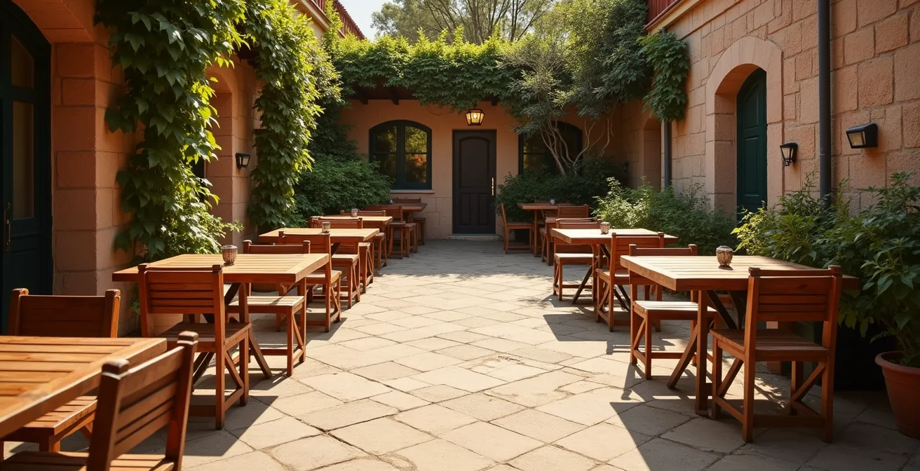 Terrasse ensoleillée d'une pizzeria avec tables en bois et plantes méditerranéennes